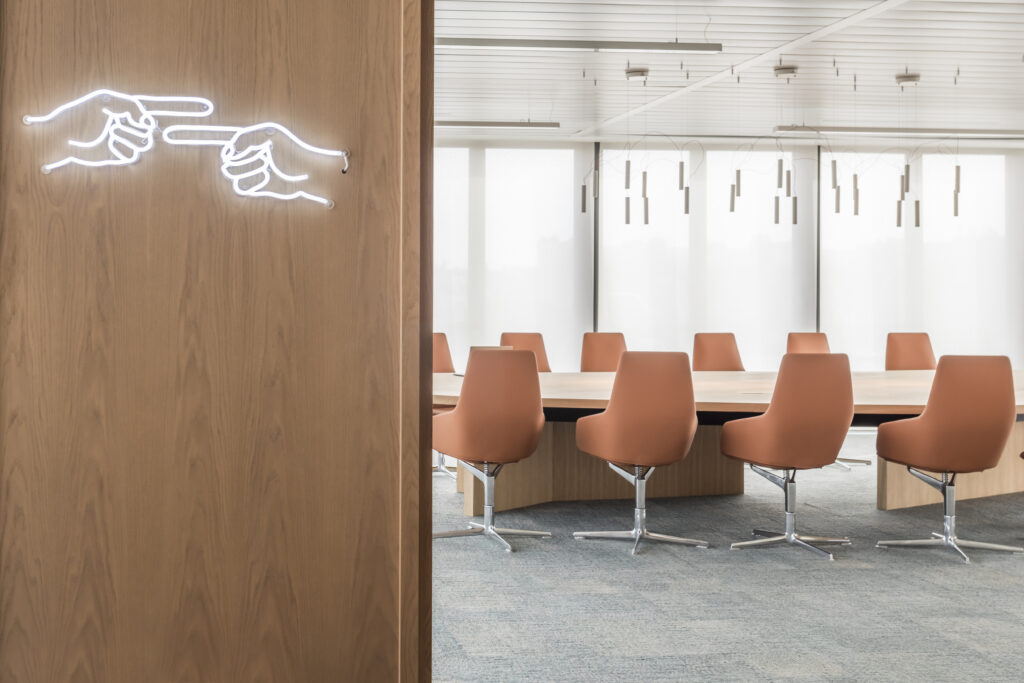 Salle de réunion design avec mobilier haut de gamme et enseigne lumineuse artistique sur panneau en bois. Open space et coworking